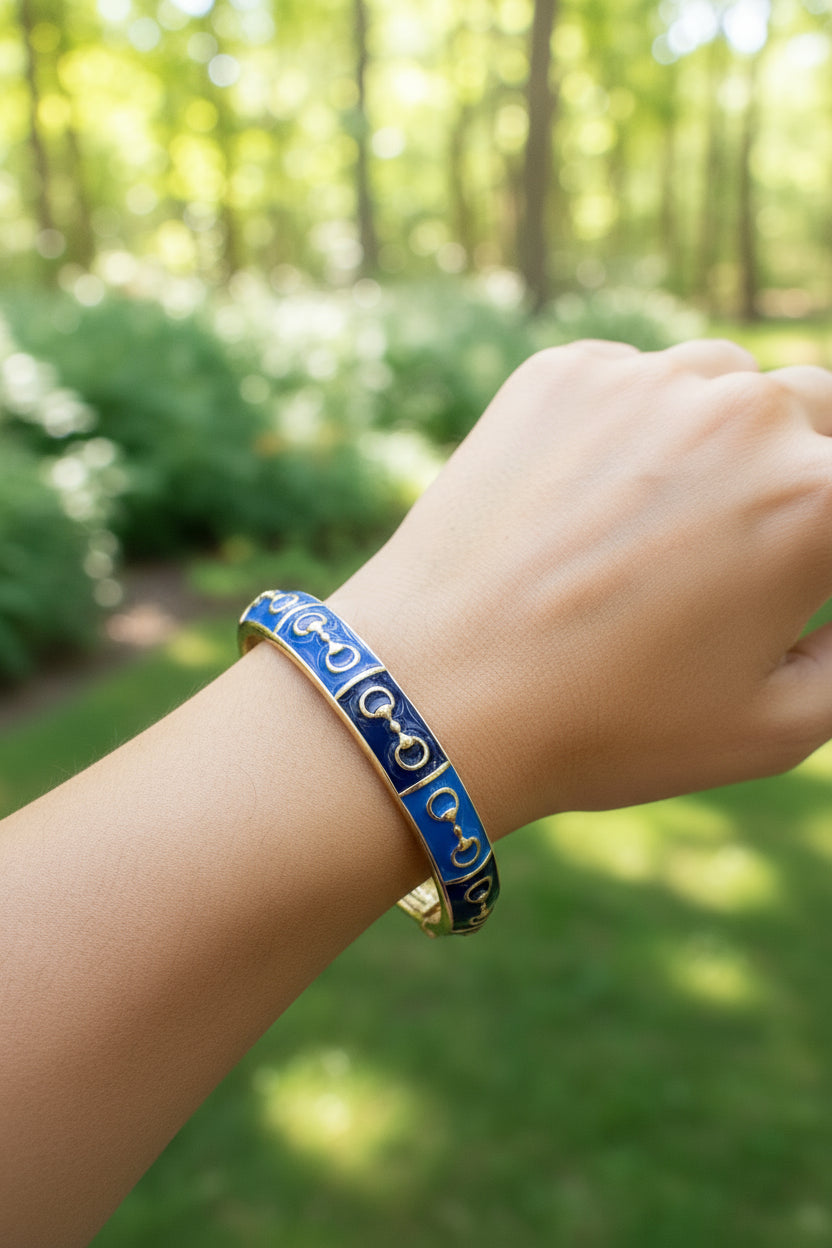 Hand wearing a blue and gold bracelet with a blurred forest background