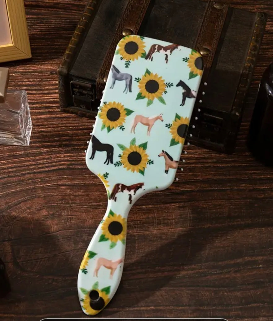 light green paddle brush with sunflowers and horse designs on a vanity