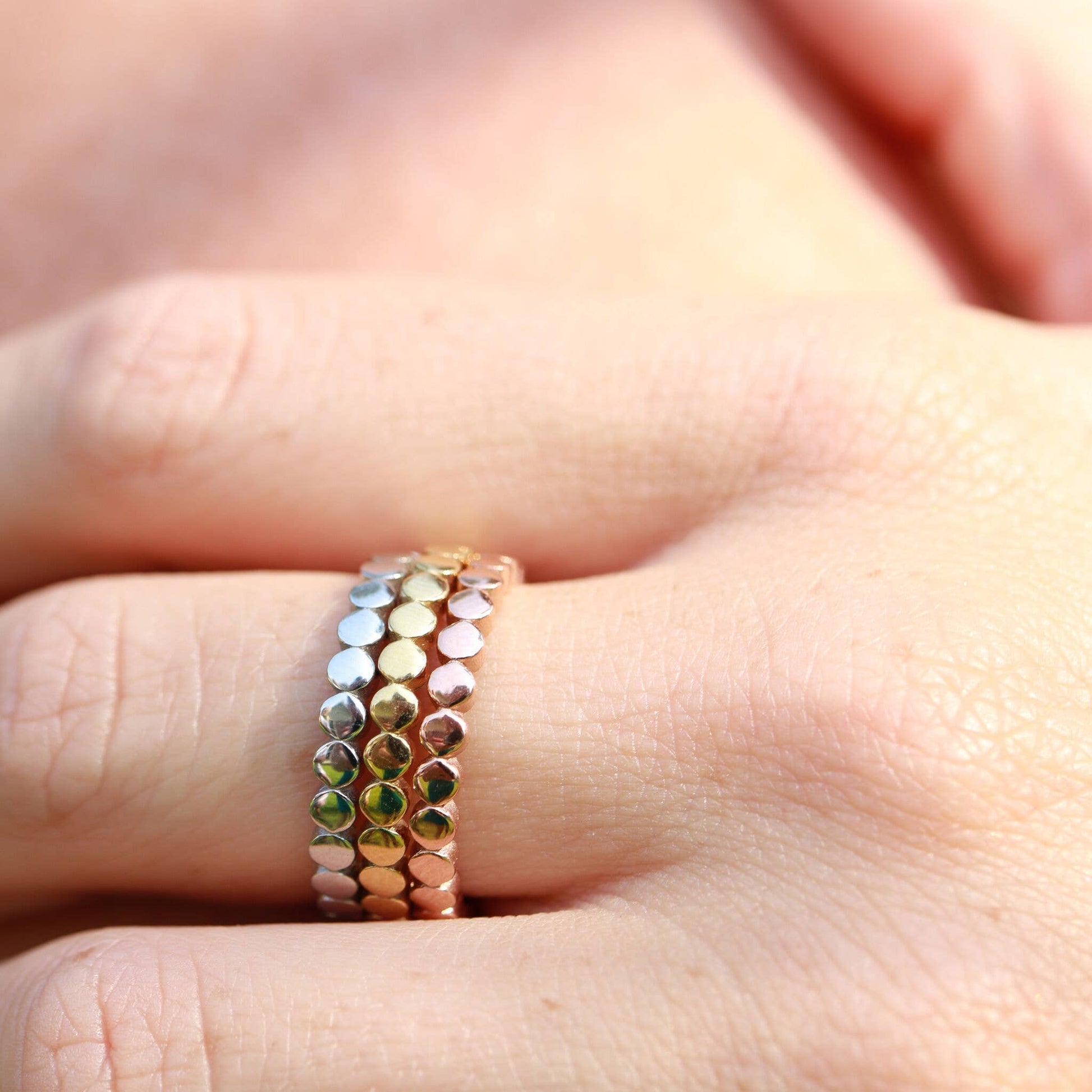 Stack of beaded rings on a finger with a blurred background