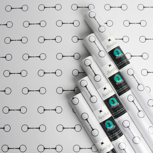Rolls of white paper with black and teal labels on a horse bit patterned background