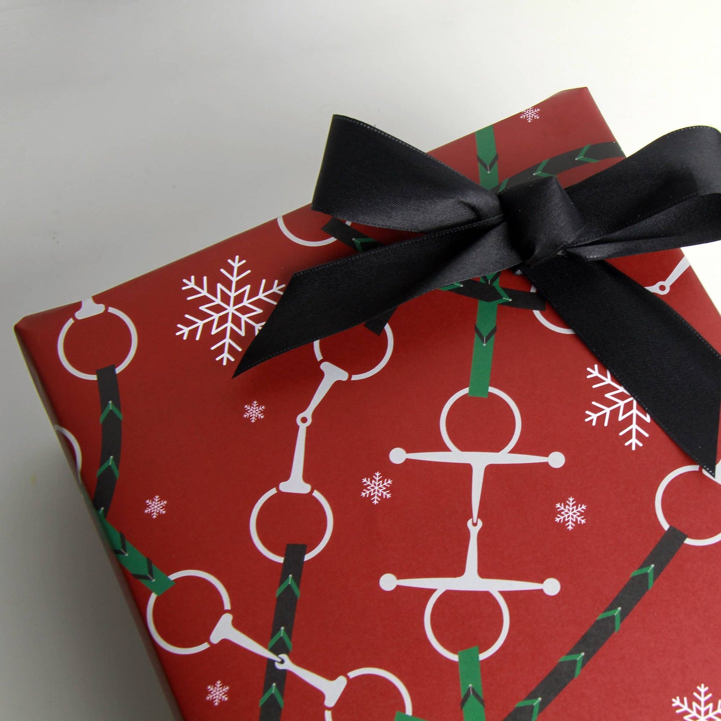 Red Christmas Equestrian wrapping paper, with snaffle bits and reins along with white snow flakes