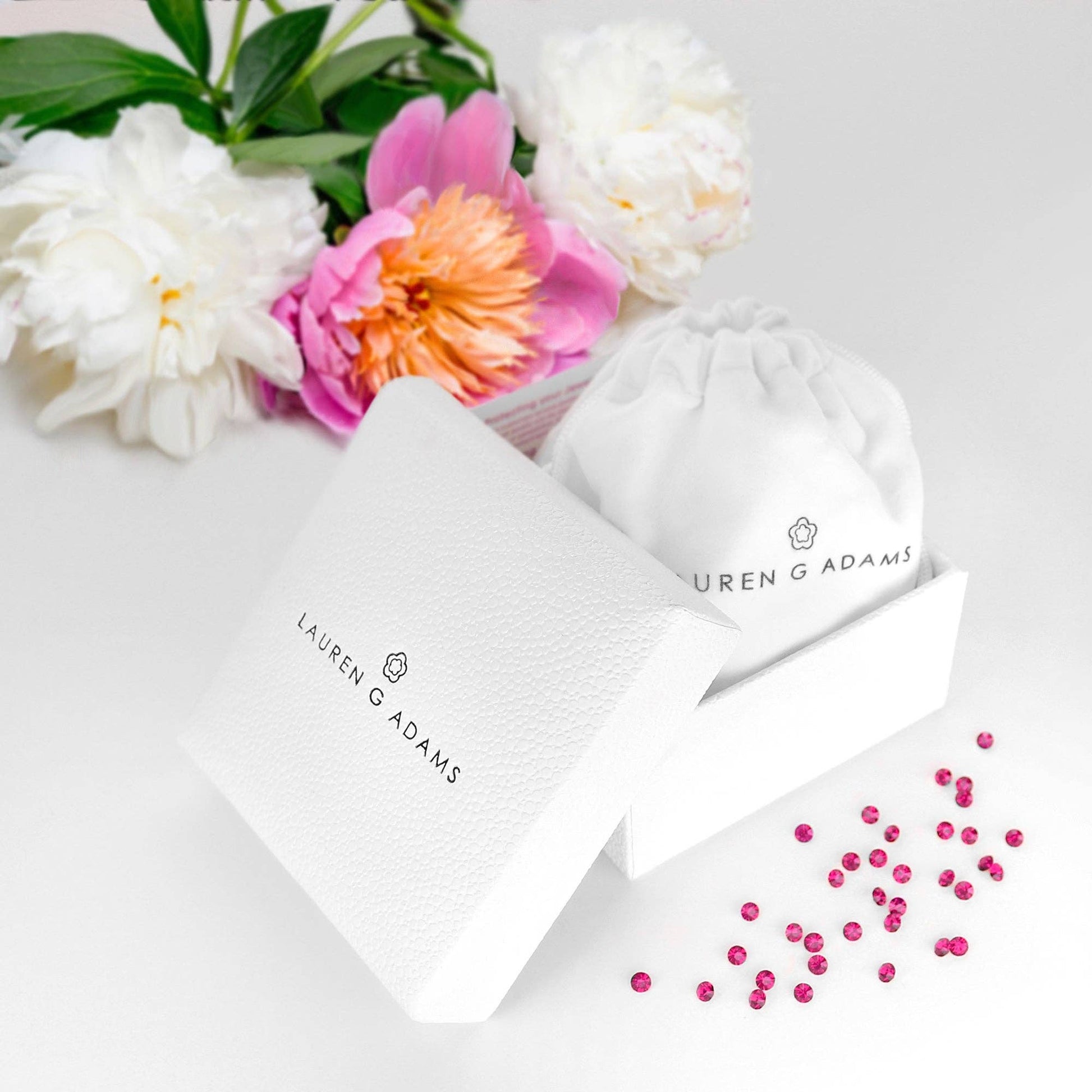 White drawstring bags with 'Lauren G Adams' logo, pink flowers, and green leaves on a white background.