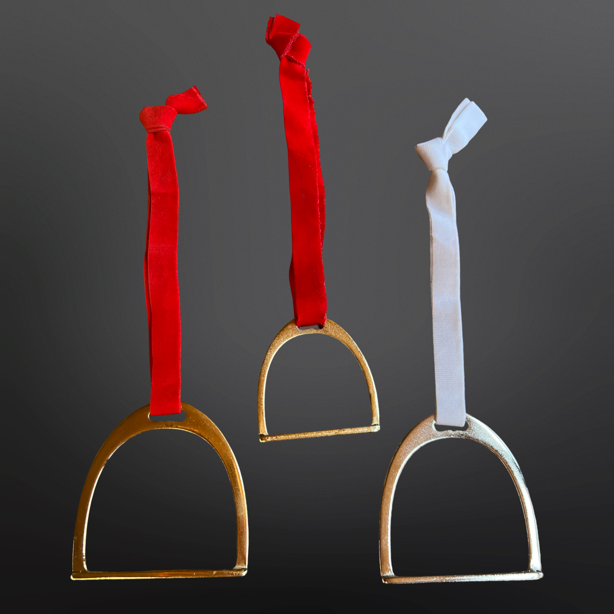 Three metal stirrups with red and white straps on a dark background, christmas ornaments on display