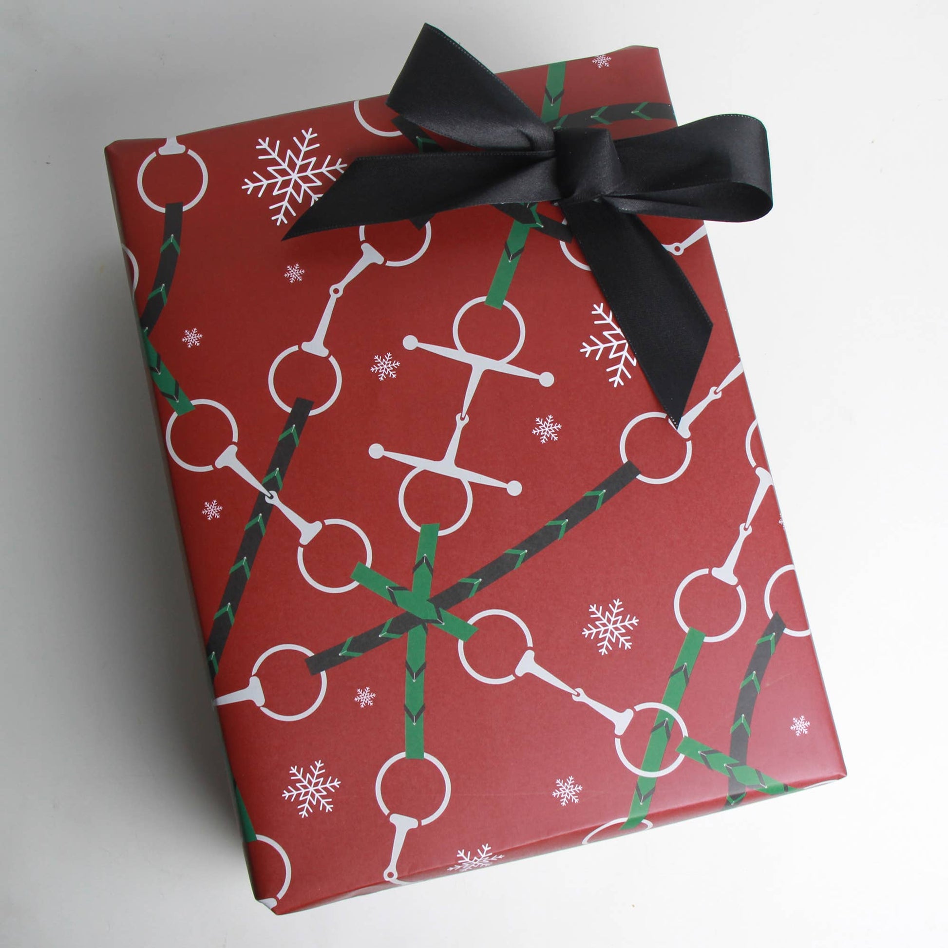 Red christmas wrapping paper, with snaffle bit designs, used for equestrian gifts