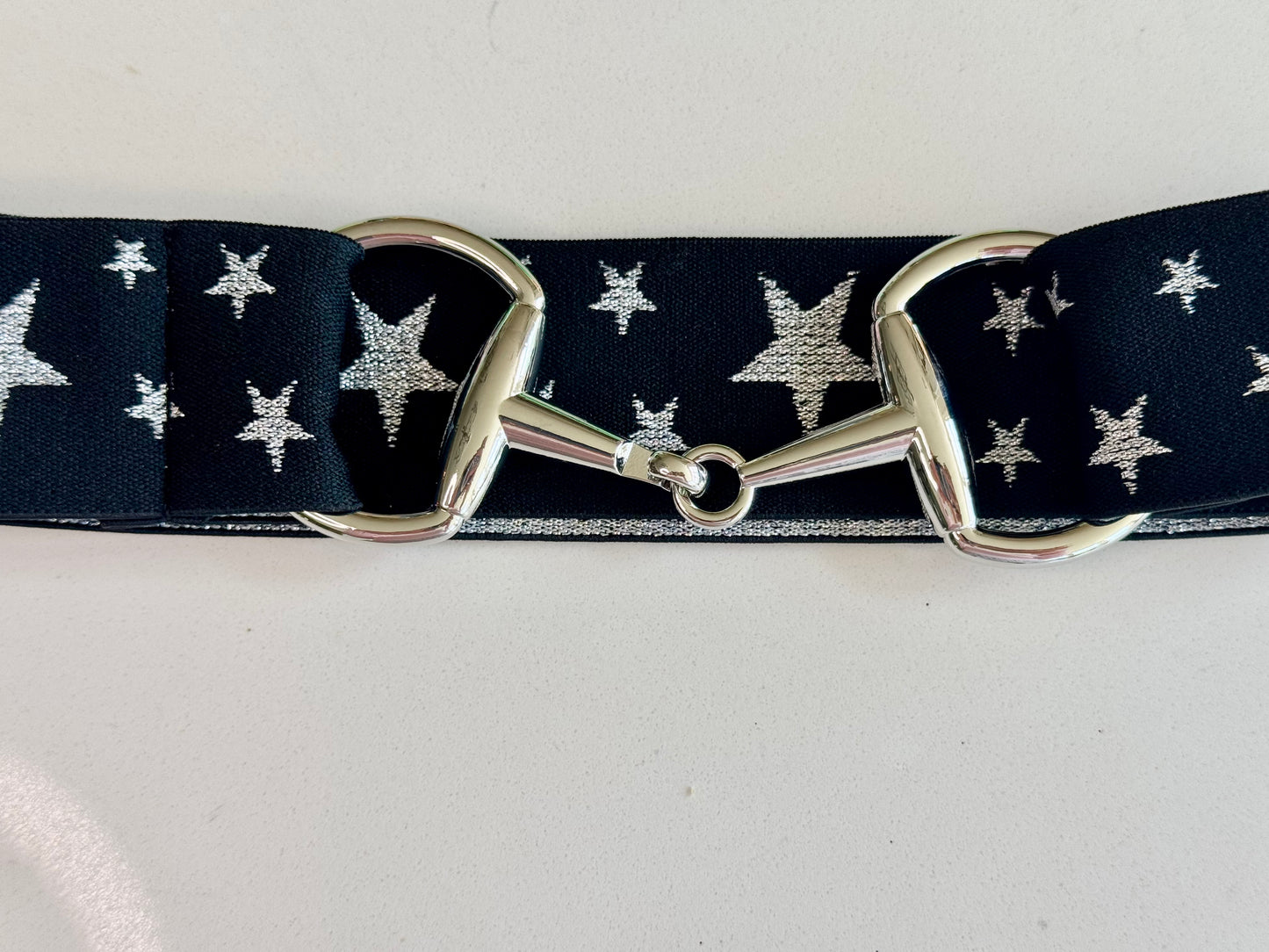 A collection of three sparkle bit belts in silver, purple, and blue colors with chrome hardware and a snaffle bit buckle closure.