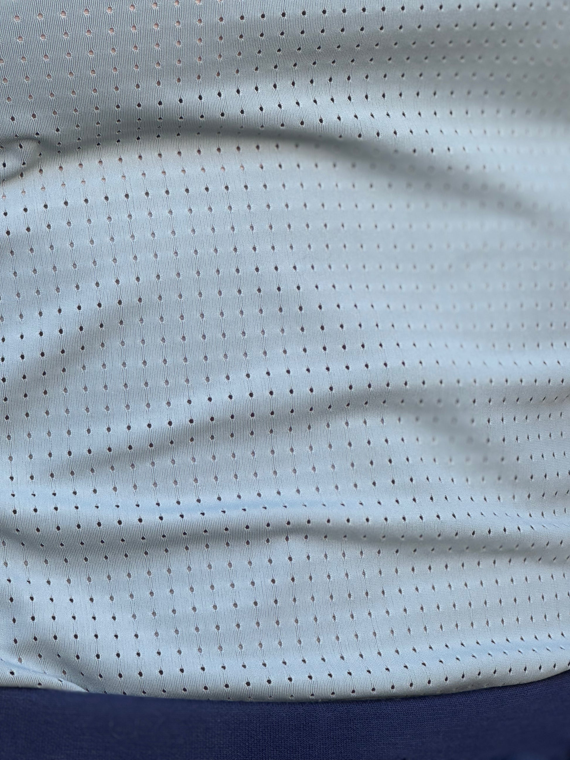 Close-up of a seafoam perforated fabric with a blue section at the bottom.