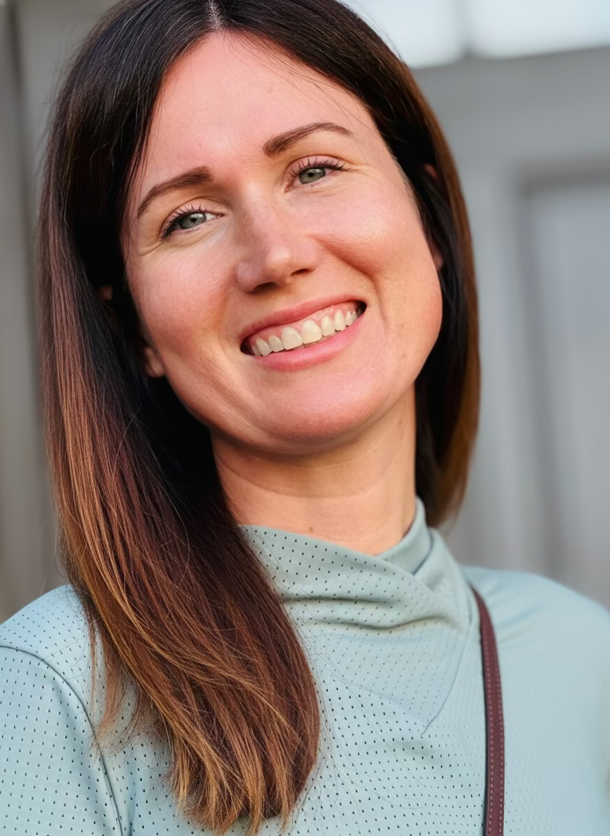 Woman with shoulder-length brown hair wearing a green mesh horseback riding top. 