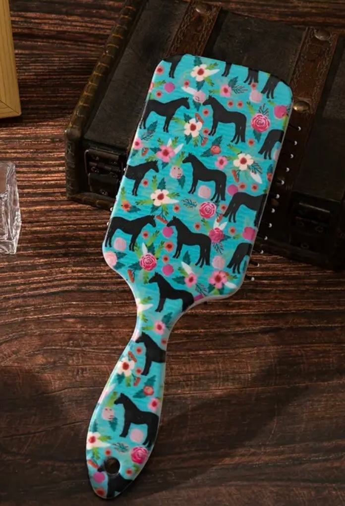 Turquoise paddle hair brush with horse and flower design, on a vanity
