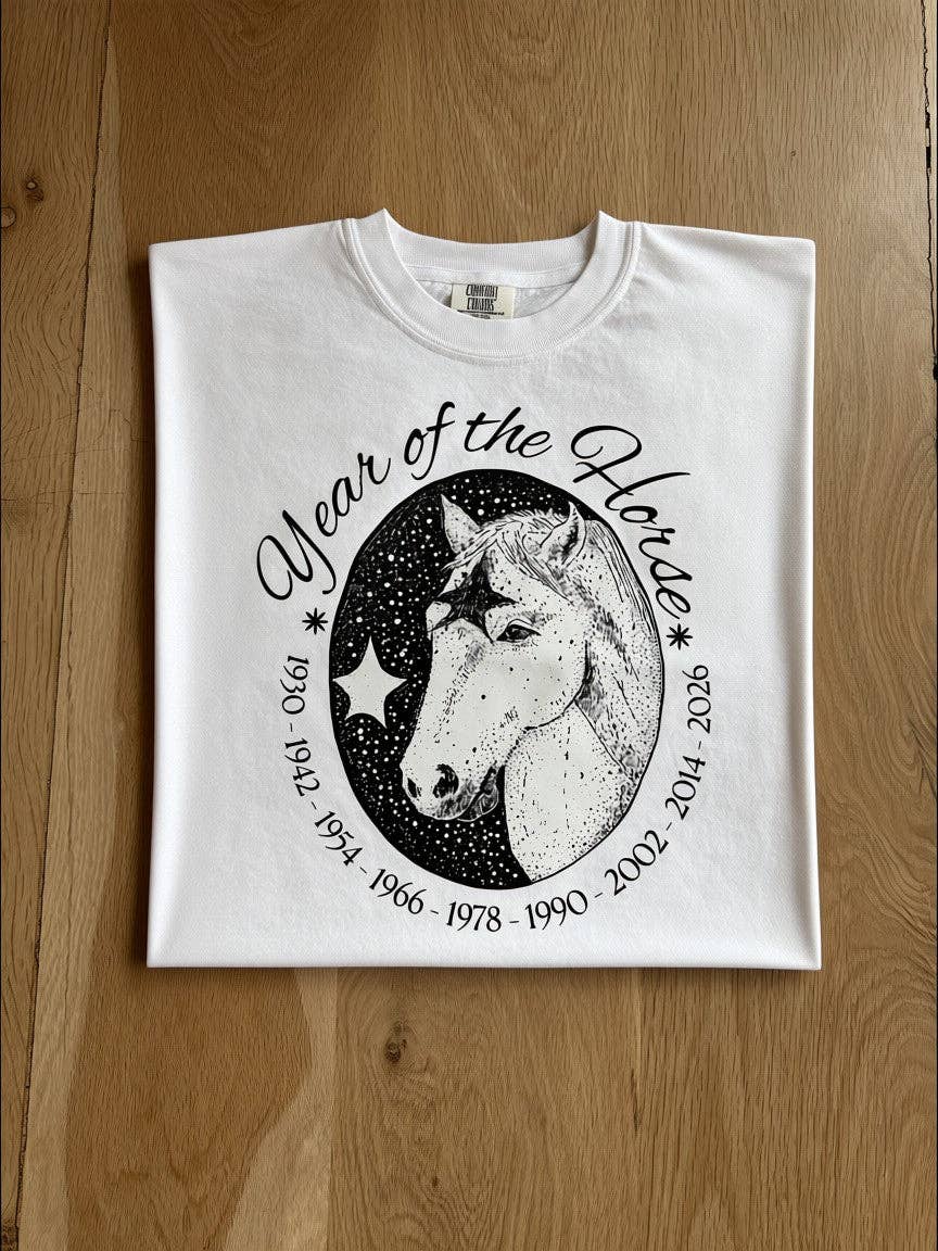 White t-shirt with a year of the horse graphic on a wooden table