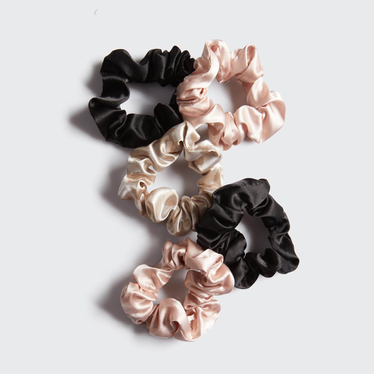 A 5-piece set of satin riding scrunchies in black, blush, and leopard print, designed for under-helmet wear and preventing hair breakage
