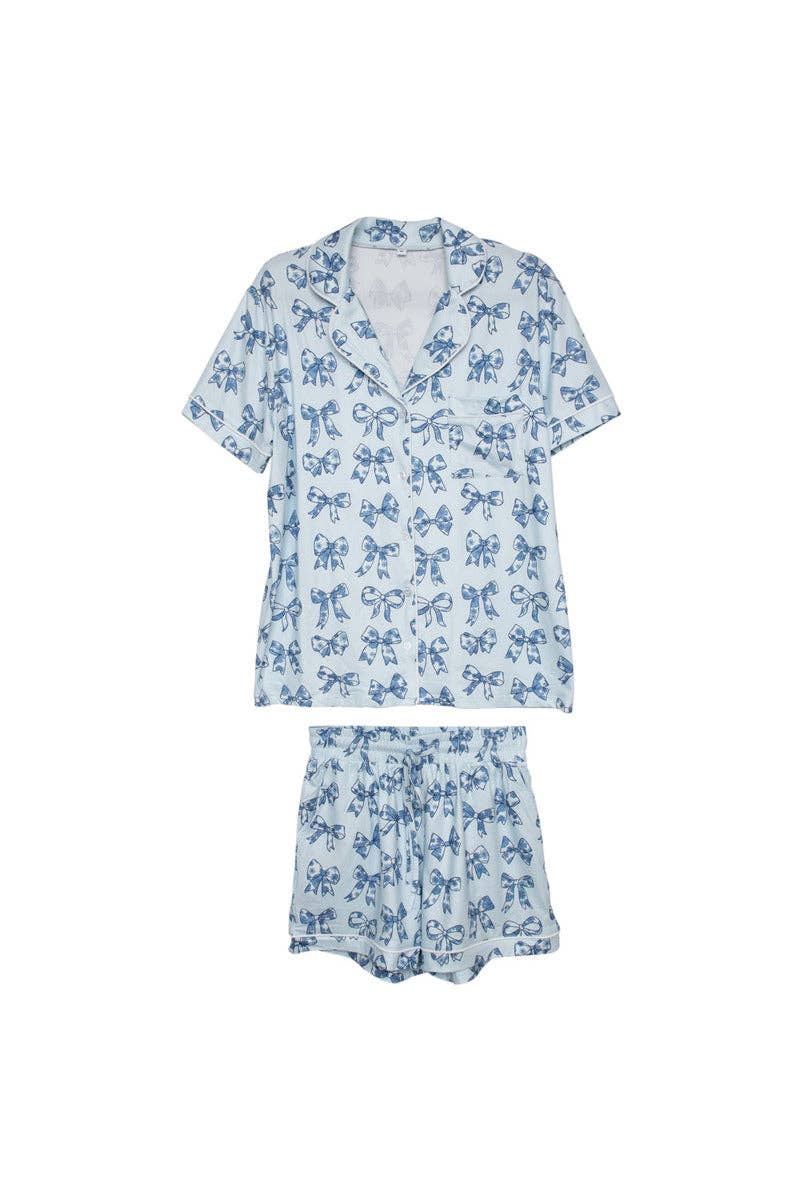 A woman standing in a kitchen wearing a blue and white floral pajama set with short sleeves and shorts, holding a white mug. equestrian inspired