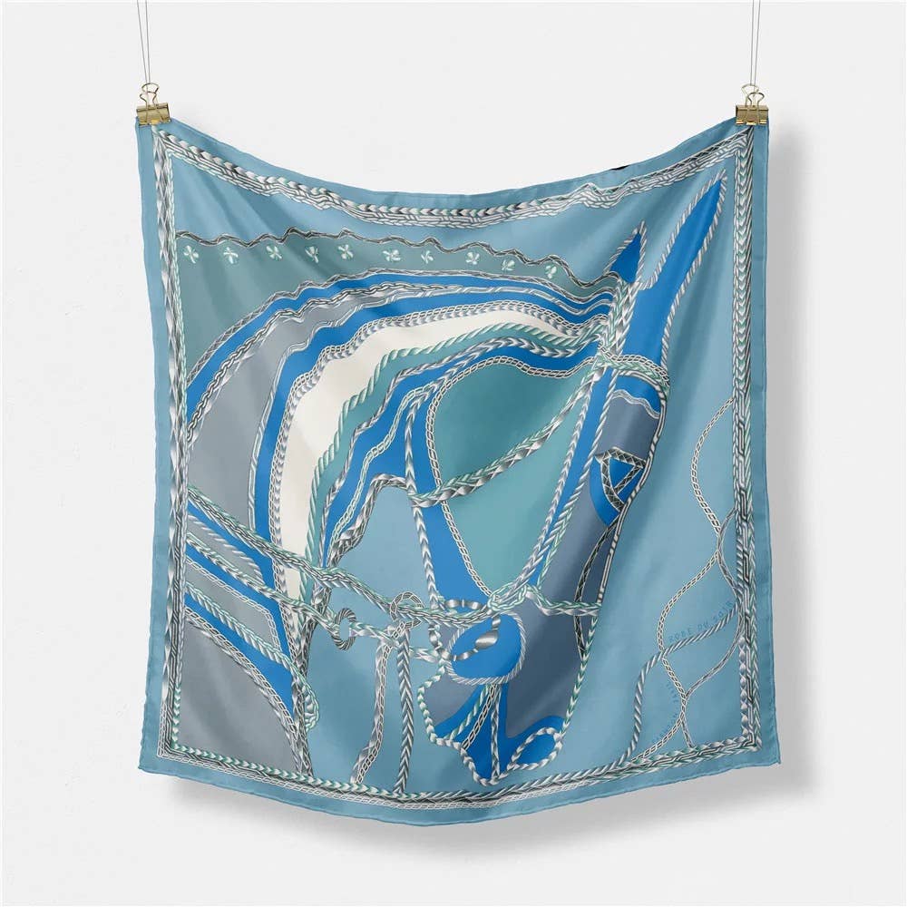 blue silk horse head designed scarf on white back ground, hanging from silver clips