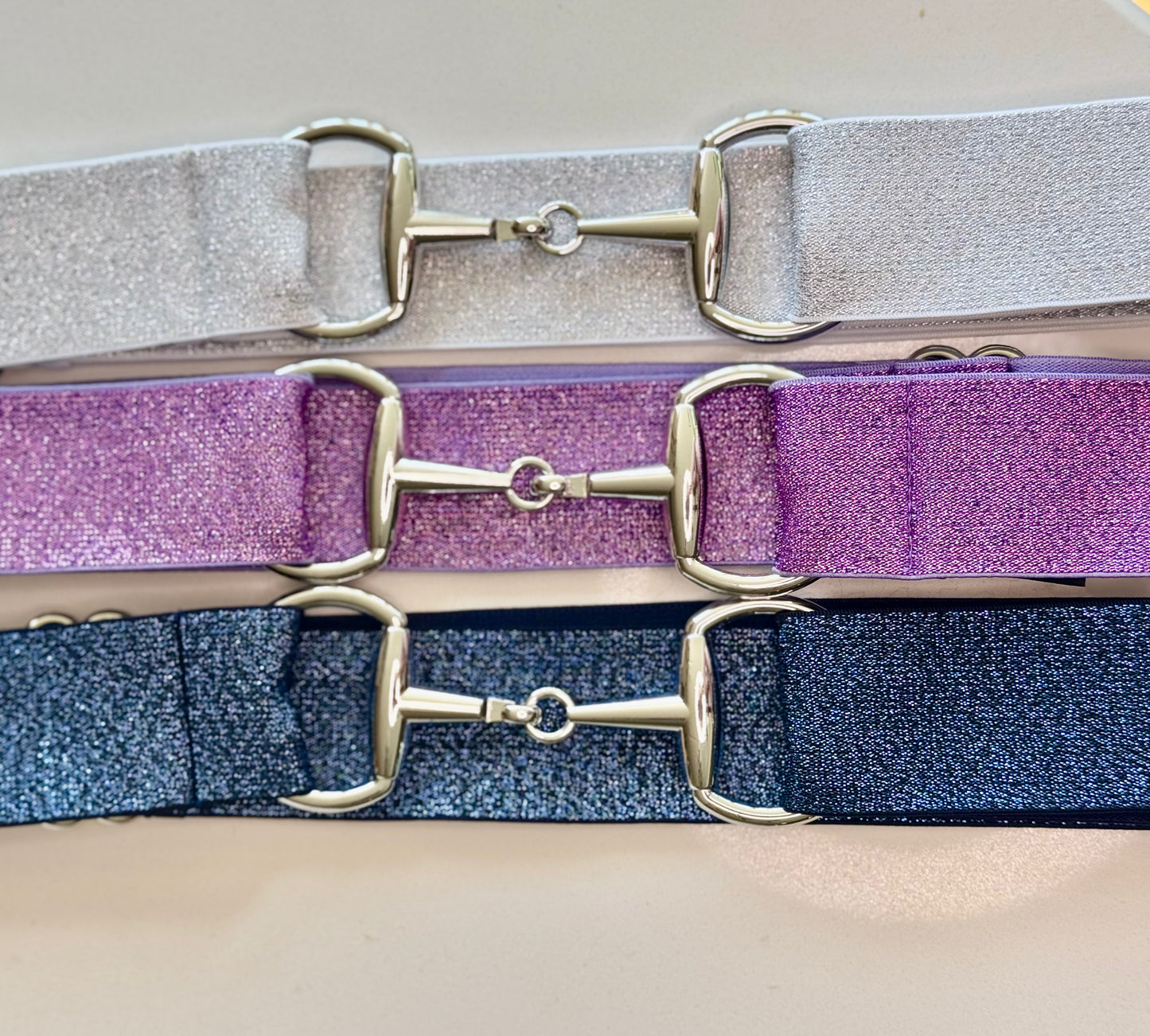 A collection of three sparkle bit belts in silver, purple, and blue colors with chrome hardware and a snaffle bit buckle closure.