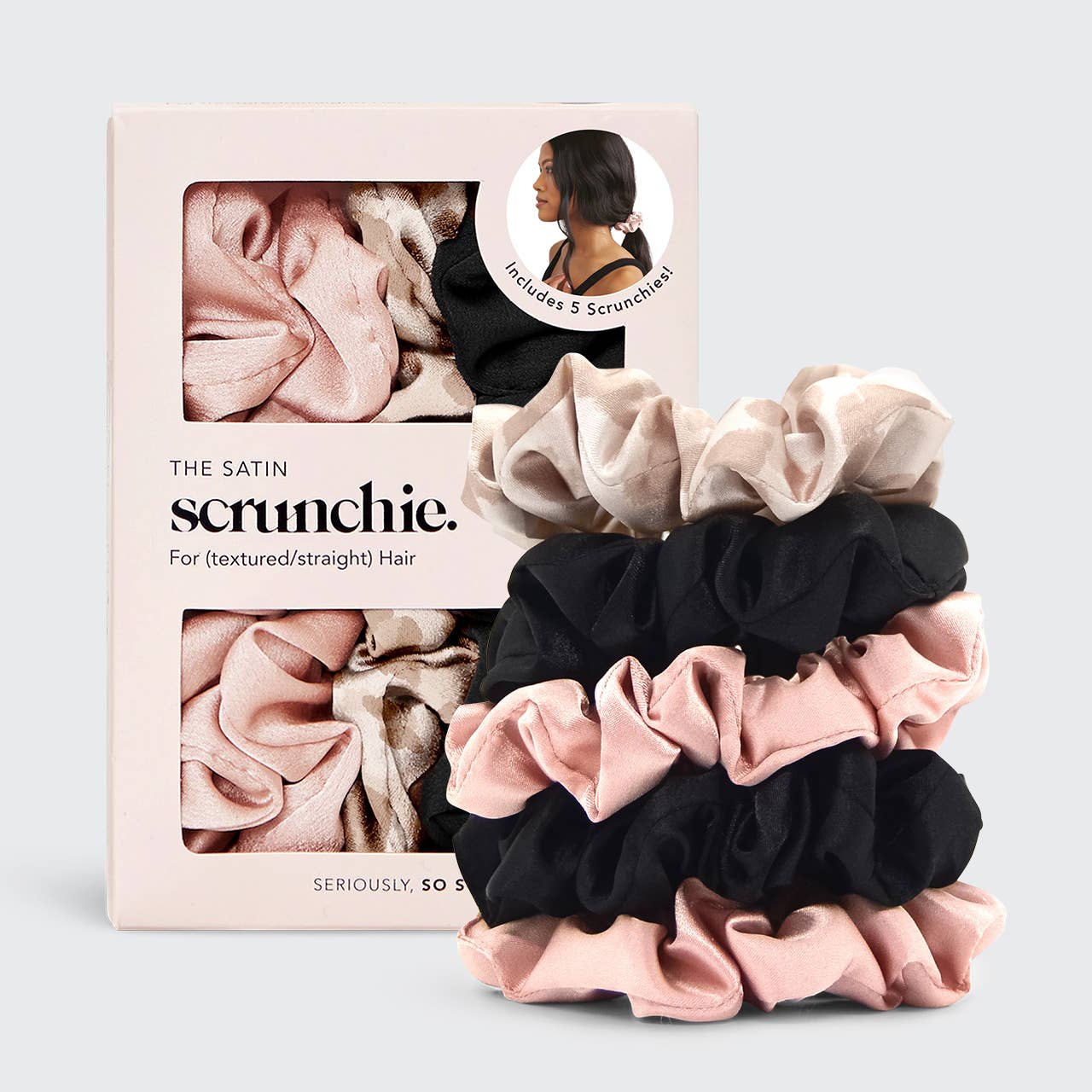Five satin scrunchies in assorted black, blush, and pink colors, displayed in a packaging that states 'The Satin Scrunchie' and 'Seriously Soft Hair'.