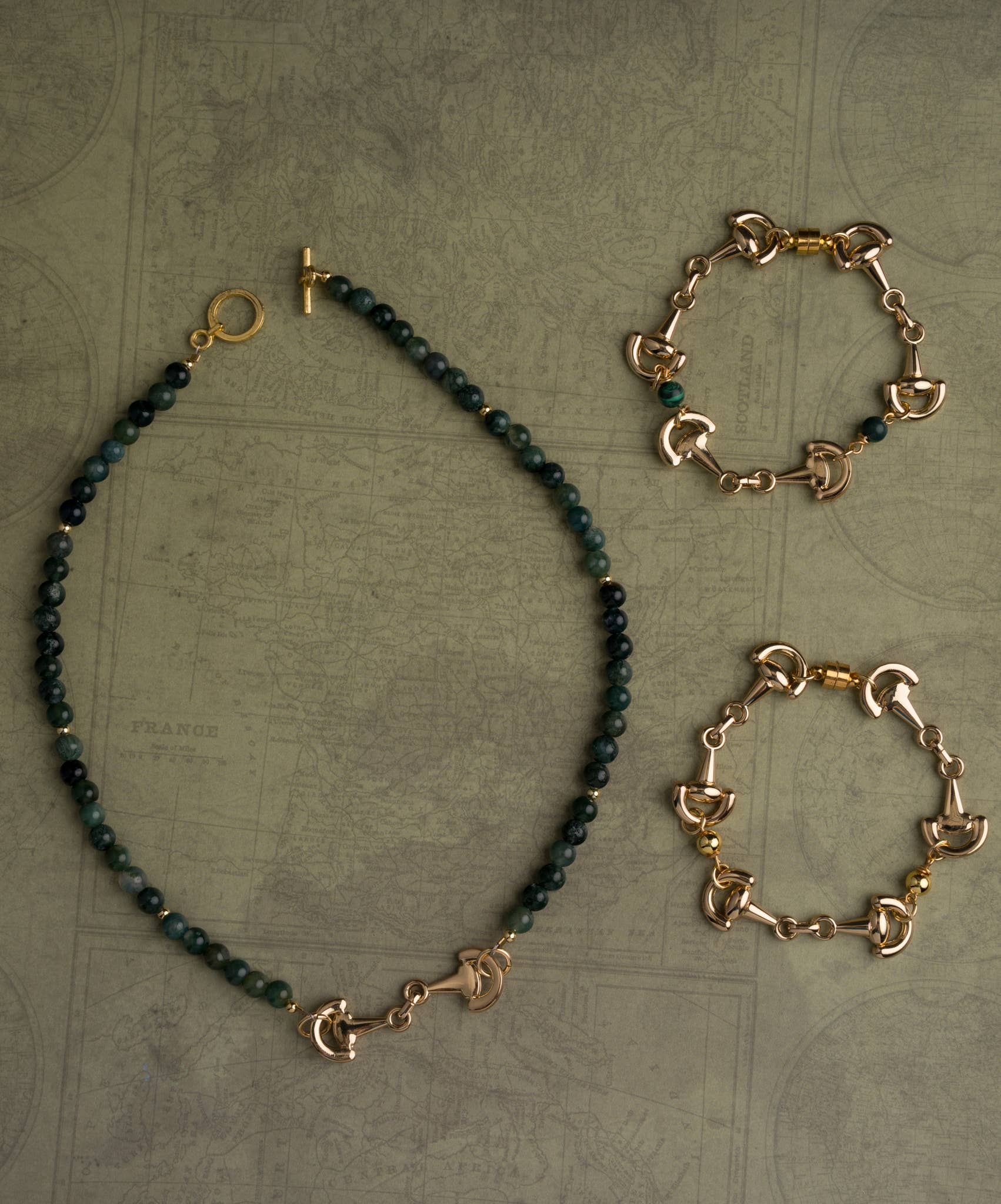 Gold and green beaded equestrian jewelry set on a textured surface