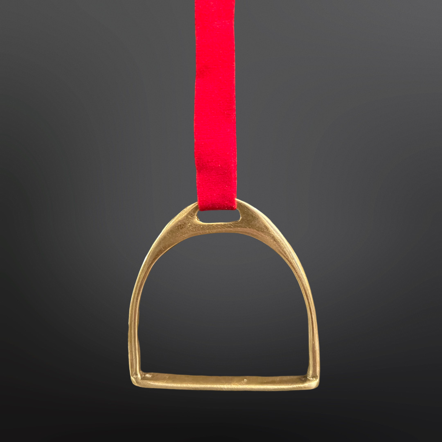 Gold stirrup with a red ribbon on a black background