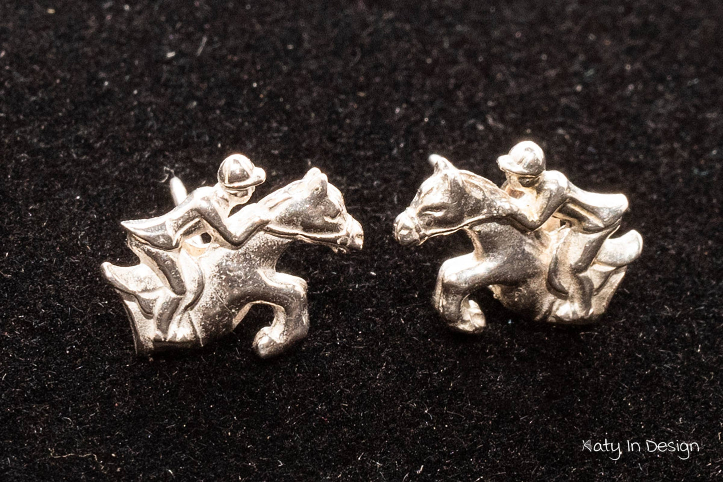 A pair of sterling silver stud earrings featuring a horse and rider design.