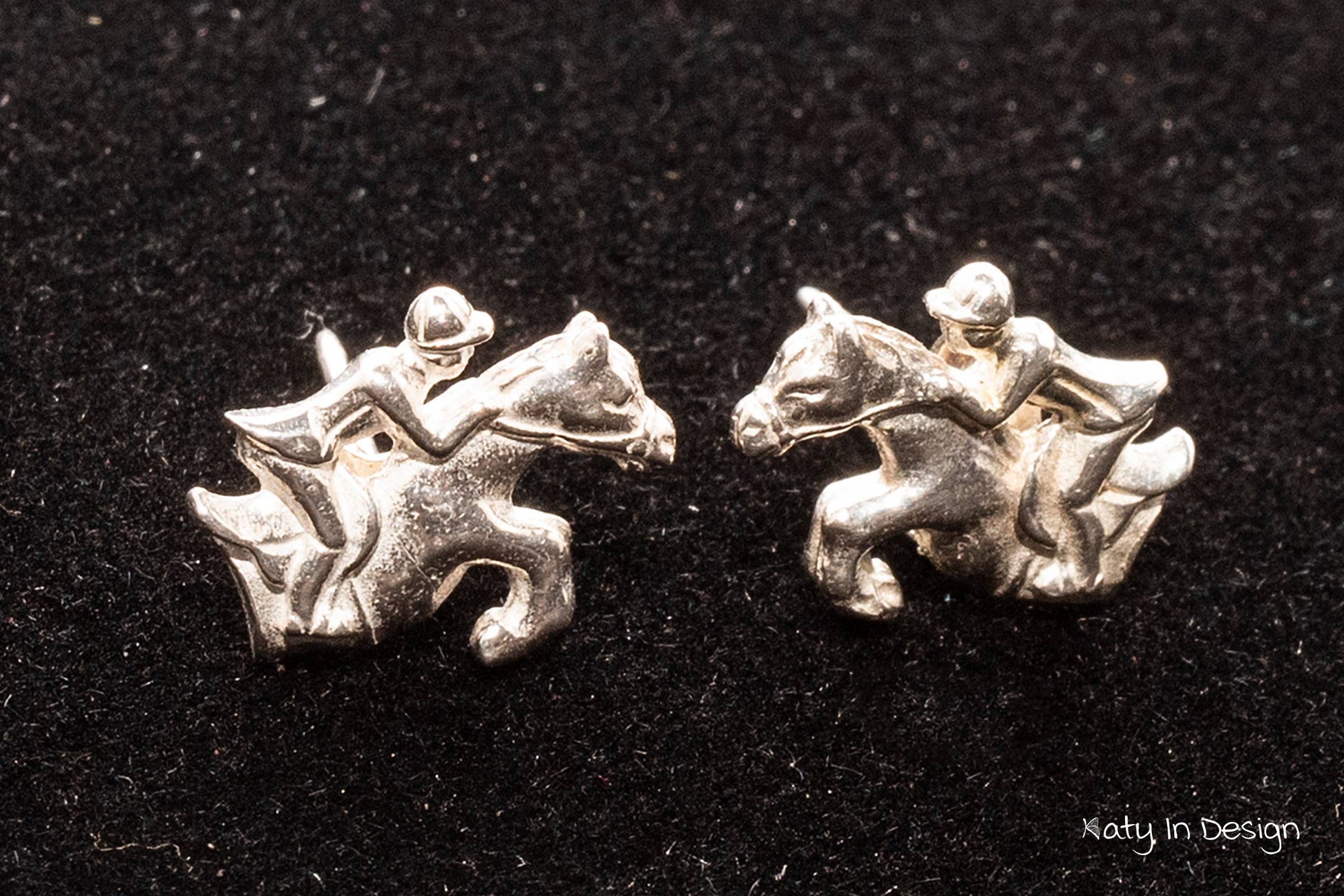 A pair of sterling silver stud earrings featuring a horse and rider design.