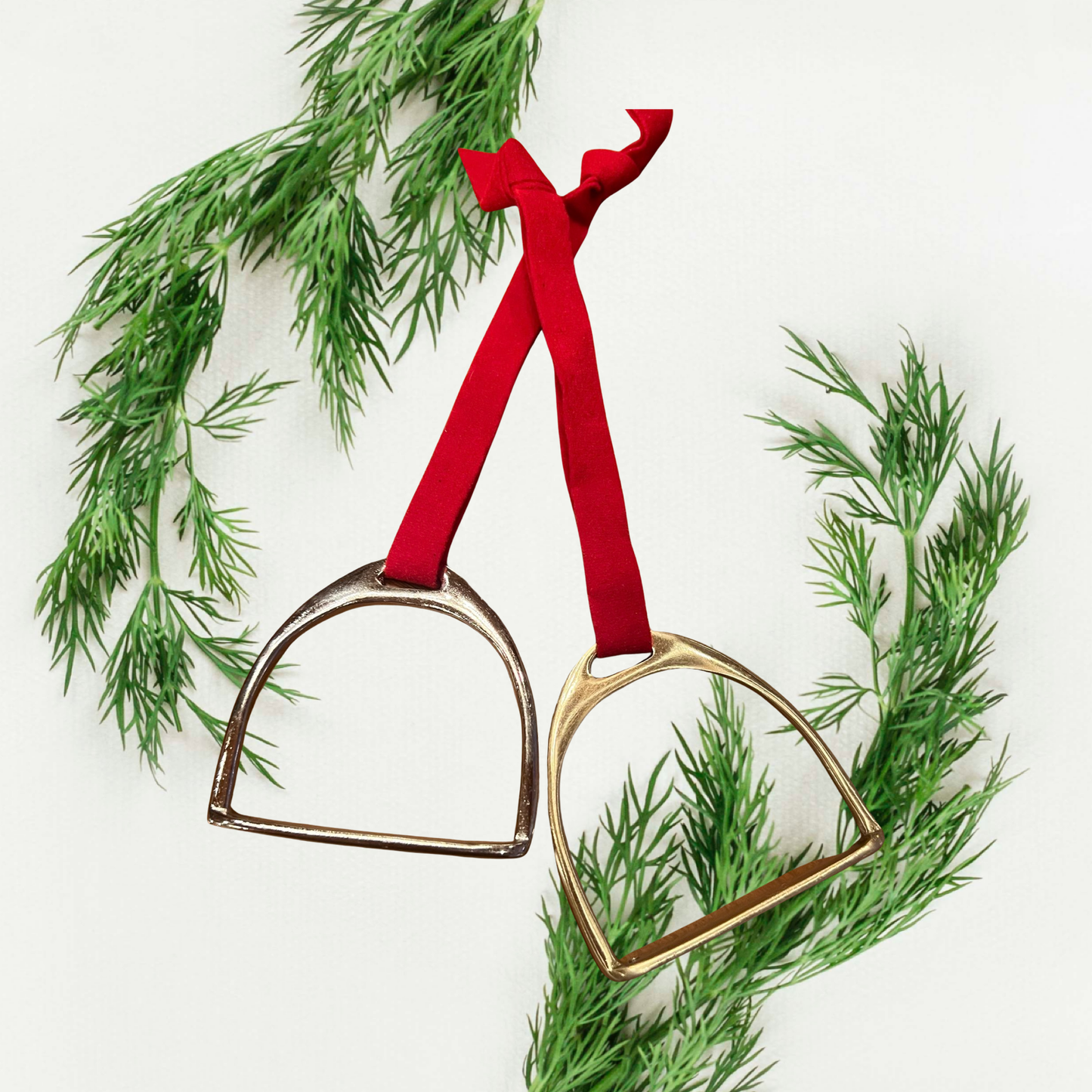 Gold horse shoe ornaments with red ribbons on a christmas tree branch