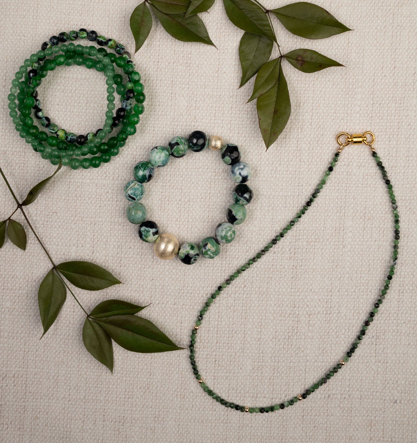 Set of green beaded equestrian jewelry including bracelets and a necklace on a beige background with leaves.