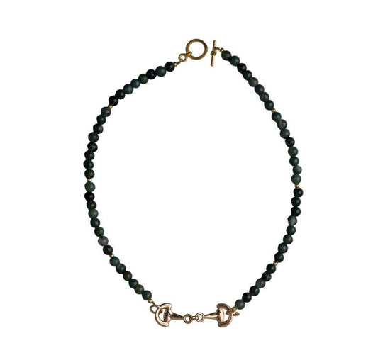 Green beaded necklace with gold horsebit pendant and gold clasp on a white background