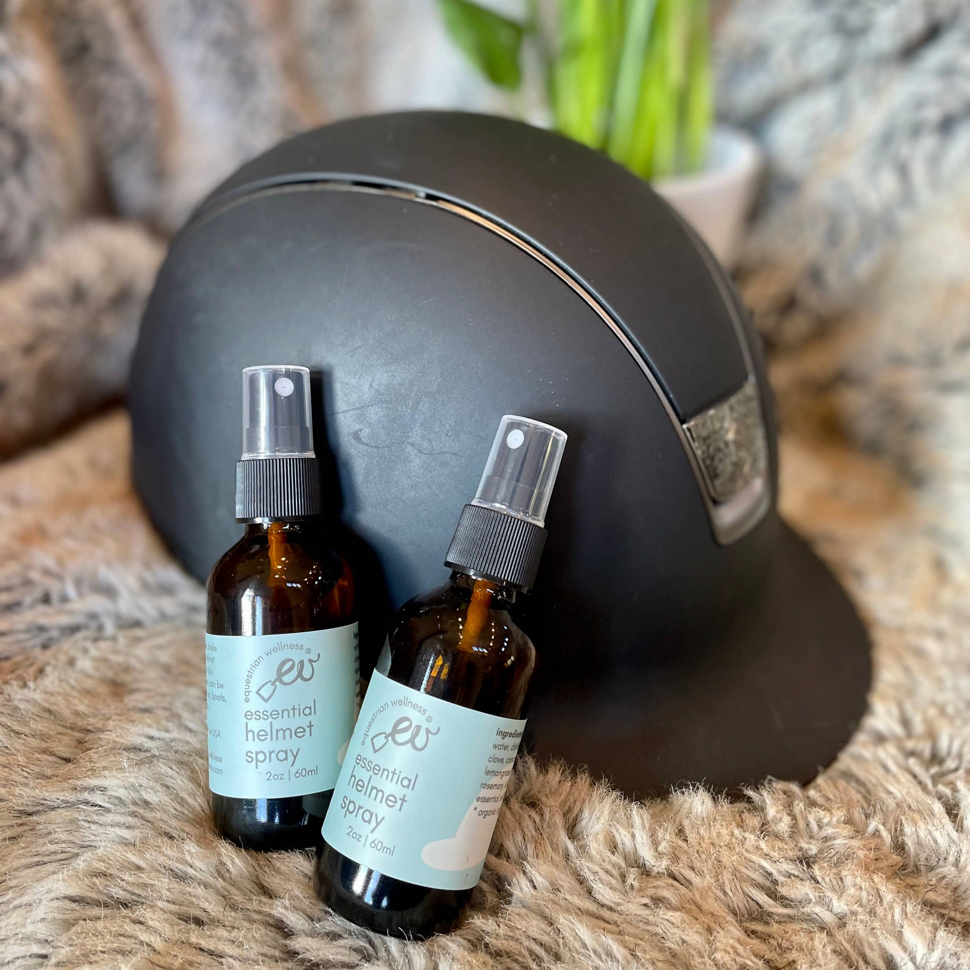an equestrian black riding helmet with two bottles of organic essential oil helmet spray to deodorize helmets. Display to show best equestrian gifts