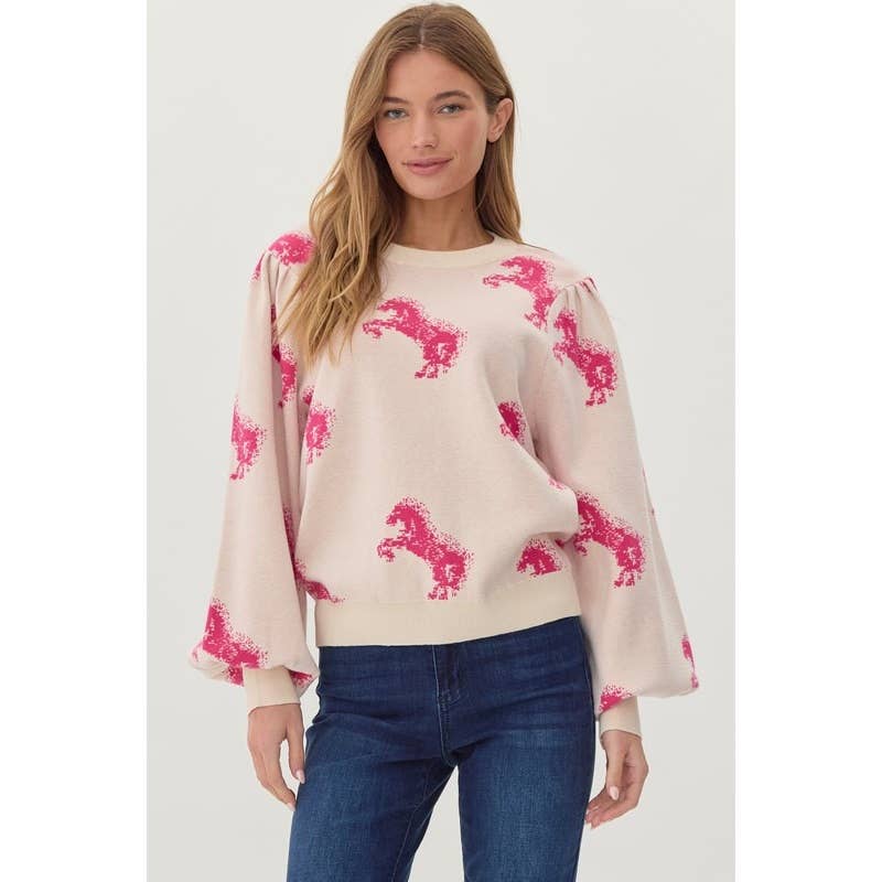 A woman wearing a beige knit sweater top with a horse pattern and long sleeves, paired with blue jeans.
