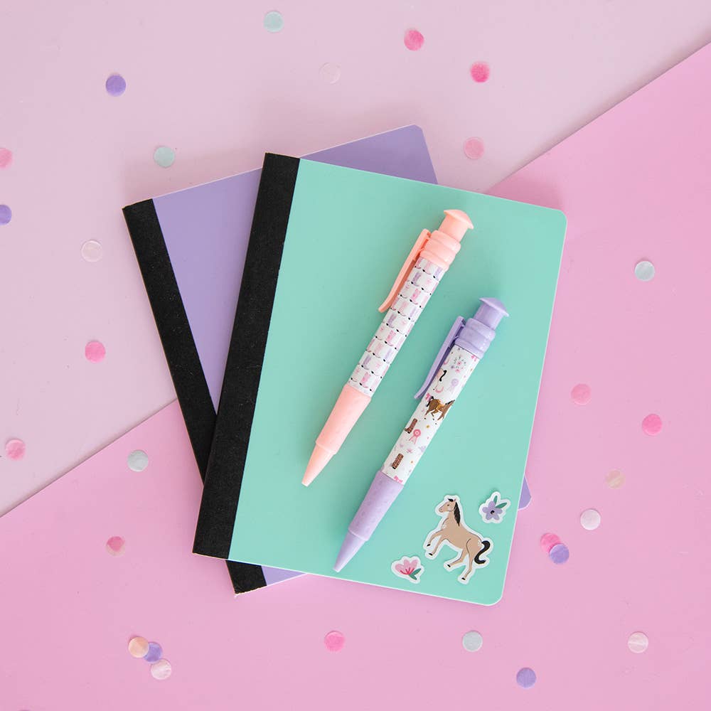 Two notebooks and two cowgirl pens on a pink and purple checkered background with confetti.