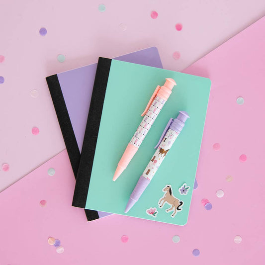 Two notebooks and two cowgirl pens on a pink and purple checkered background with confetti.