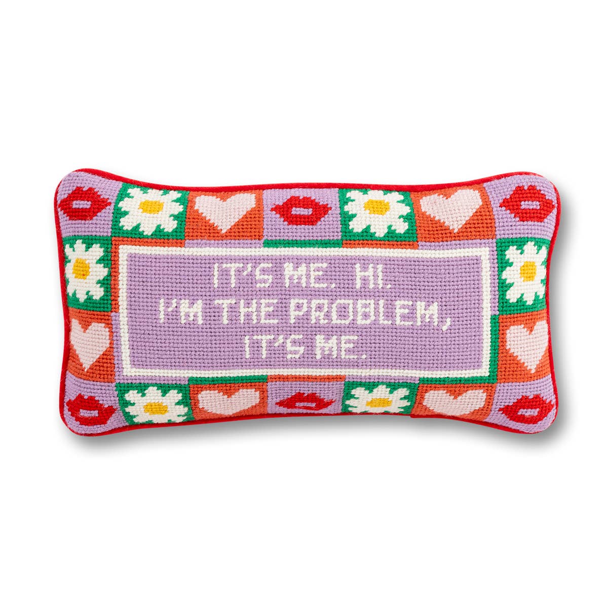 A colorful needlepoint pillow with a pattern of lips, hearts, and flowers, featuring  taylor swift text in the center.