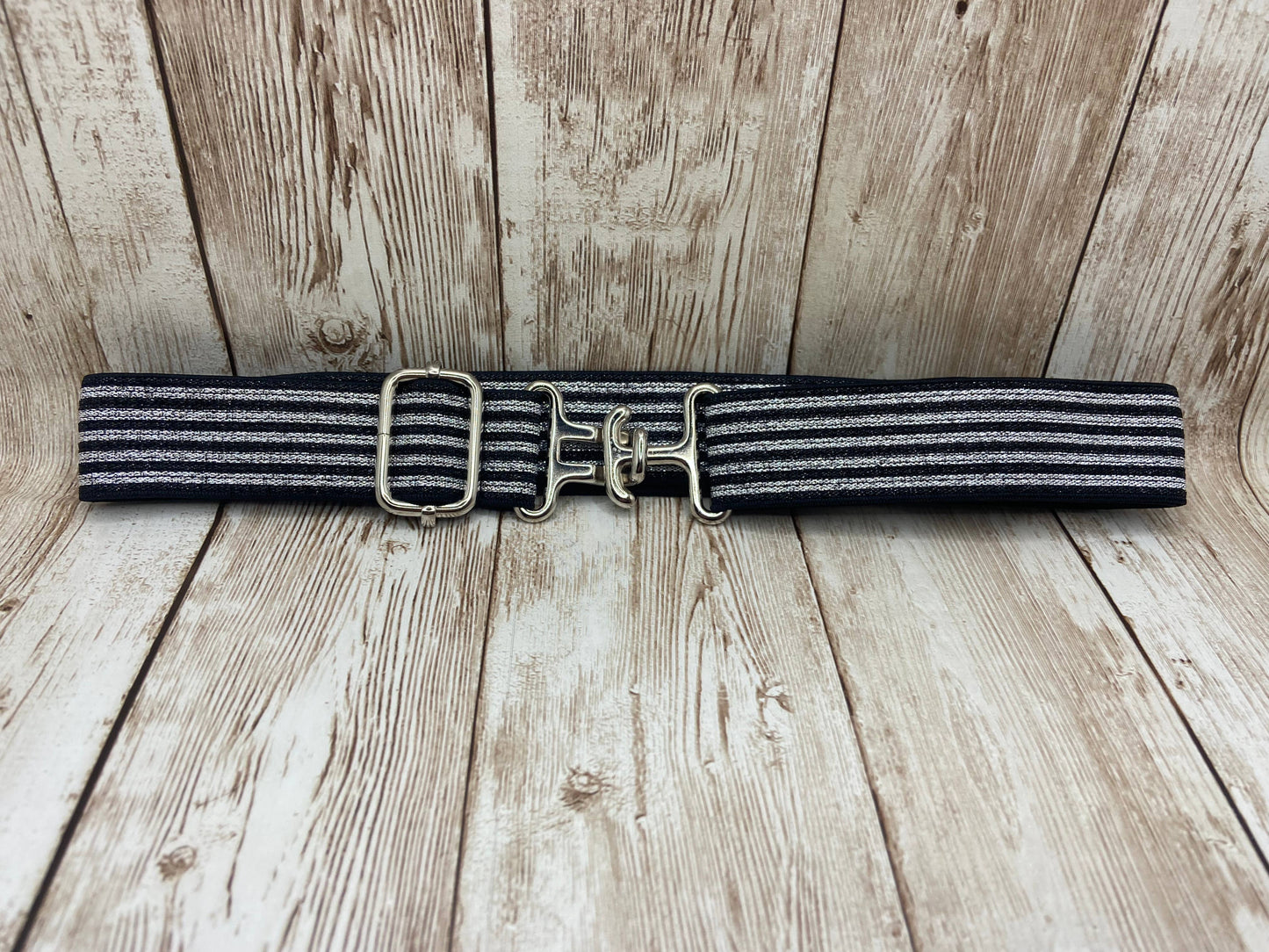 Black and gray striped belt with gold buckle on a wooden surface
